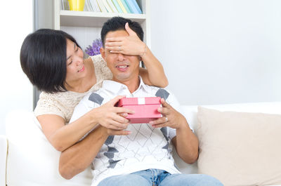 Woman giving gift to man at home