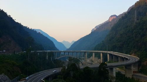 Bridge amidst mountains against sky during sunrise