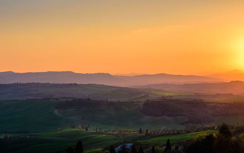 Scenic view of agricultural field against sky at sunset