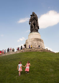 People in front of statue against sky