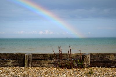 Scenic view of sea against rainbow in sky