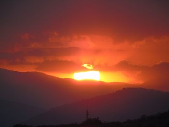 Scenic view of silhouette mountains against romantic sky at sunset