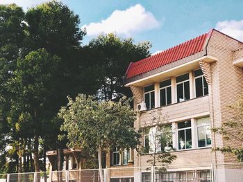 Low angle view of trees and building against sky