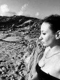 Side view of woman looking away on land against sky