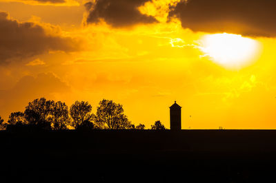 Silhouette trees against orange sky
