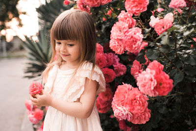 Cute girl holding flower standing outdoors