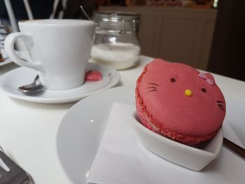 Close-up of coffee served on table with kitty shaped macaron