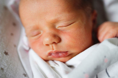 Close-up of cute baby girl lying on bed