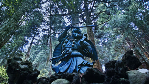 Low angle view of statue against trees in forest