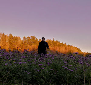 Rear view of man standing on field against sky