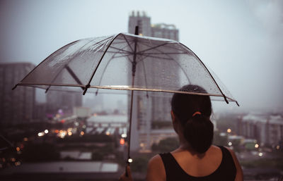 Rear view of woman with umbrella in rain