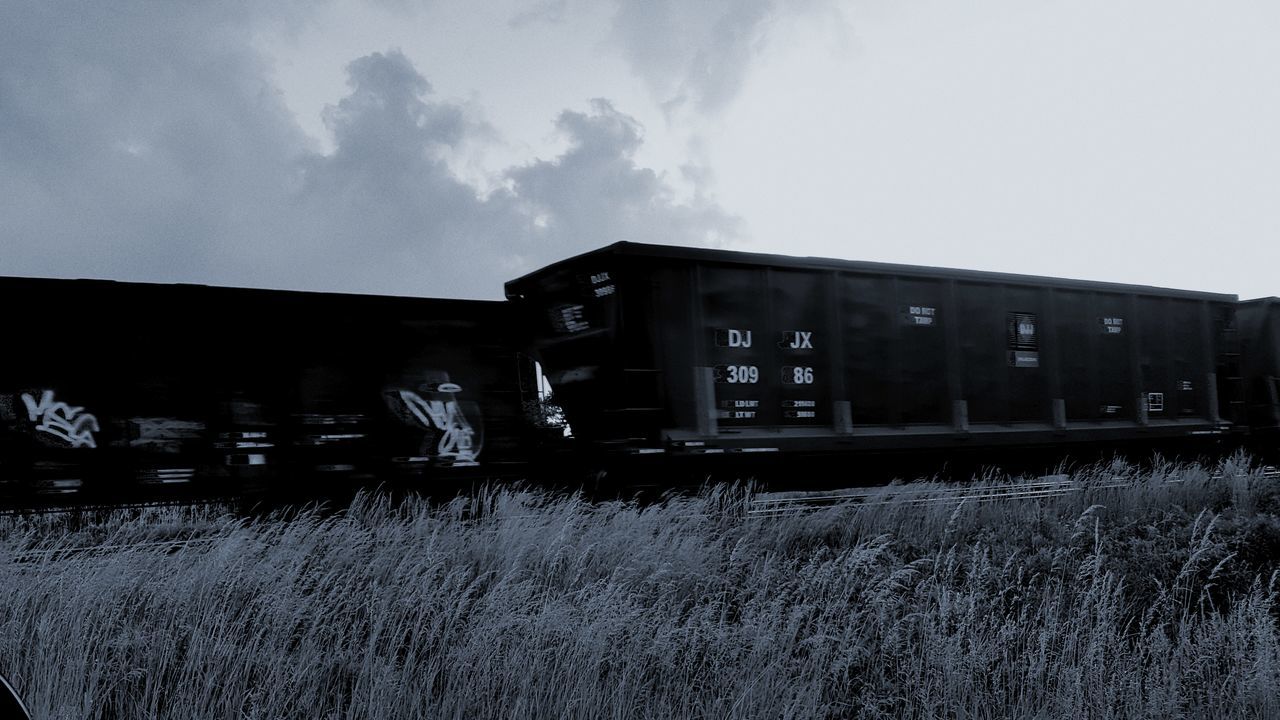 sky, grass, rail transportation, train - vehicle, outdoors, field, cloud - sky, building exterior, architecture, built structure, day, no people, nature