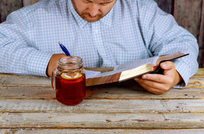 Midsection of man writing in book at table