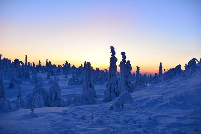 Panoramic view of snow covered land against sky during sunset