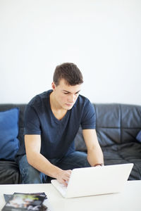 Teenage boy on sofa using laptop