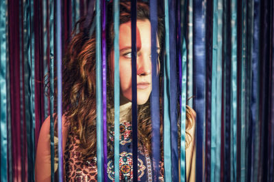 Close-up of thoughtful woman standing behind colorful ribbon