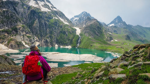 Rear view of woman standing on rock by lake