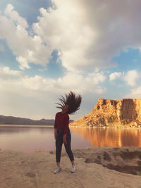 Rear view of woman standing on beach against sky