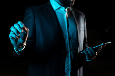 Midsection of man standing against black background