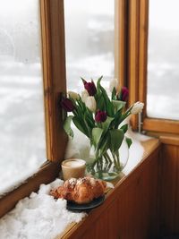 High angle view of breakfast and flowers amidst snow on window sill at home