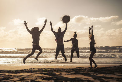 Cheerful friends enjoying on beach during sunset