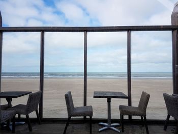 Chairs and table on beach against sky