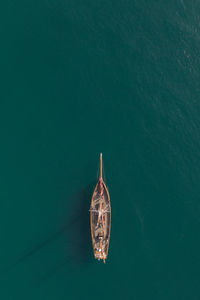  top down aerial view of a tall mast sailing boat on a calm turquoise ocean with copy space