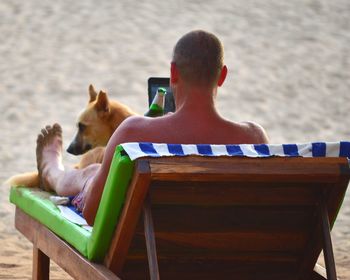 Rear view of man sitting on chair at shore