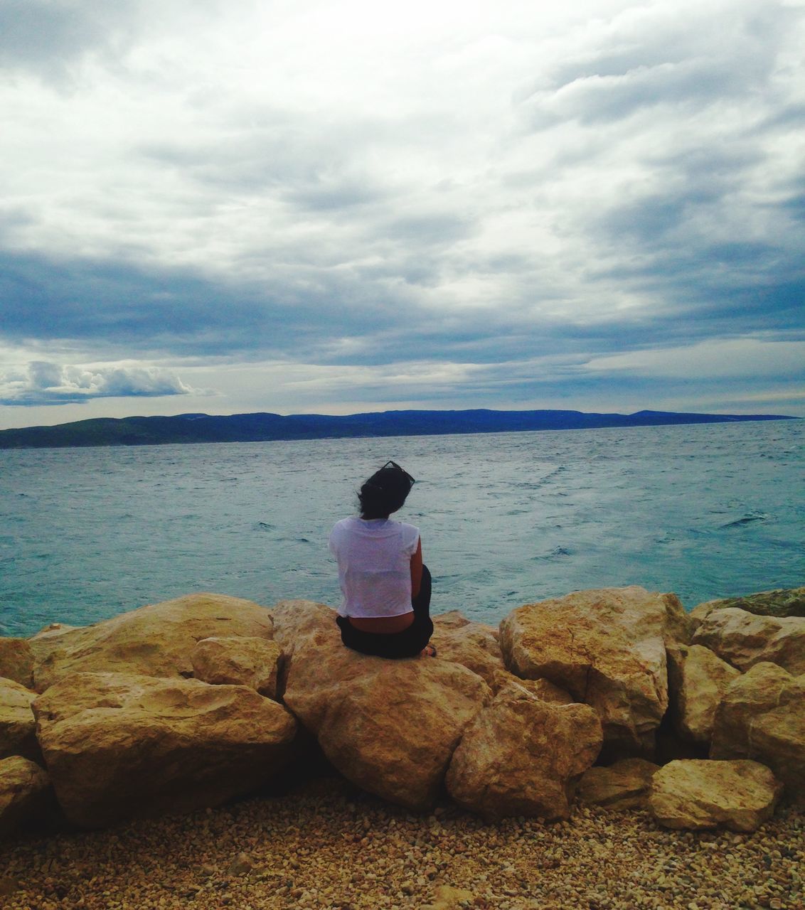 sky, water, sea, cloud - sky, lifestyles, leisure activity, tranquility, tranquil scene, beauty in nature, scenics, horizon over water, sitting, nature, rock - object, cloudy, cloud, shore, casual clothing, relaxation, idyllic, day, outdoors, vacations, remote, calm, non-urban scene