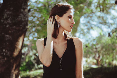 Beautiful young woman standing against trees