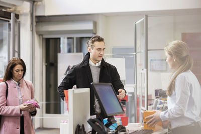 Male customer talking to woman standing at cash counter in showroom