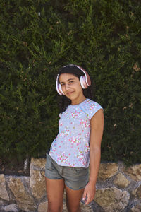 Portrait of smiling young woman standing against plants