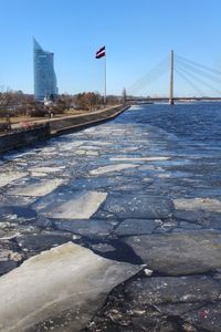 Scenic view of bridge over river against sky in city during winter
