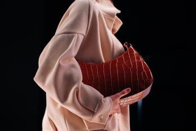 Midsection of woman holding gift against black background
