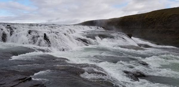 Scenic view of waterfall against sky