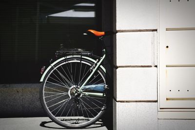 Bicycle by wall on sunny day