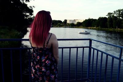 Rear view of woman looking at river against sky