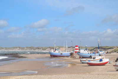 Boats moored on beach against sky