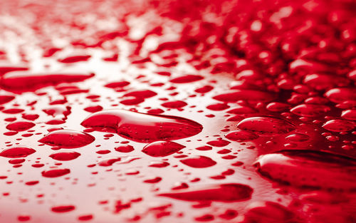 Surface level of water drops on red surface