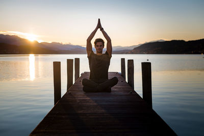 Man with arms outstretched against sky during sunset