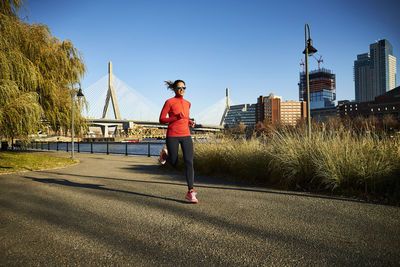 A woman running in front of the zakim bridge in boston.