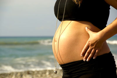 Midsection of woman with umbrella on beach