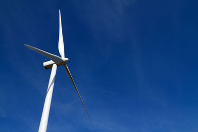 Low angle view of wind turbine against blue sky