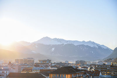 Townscape by mountains against clear sky during winter