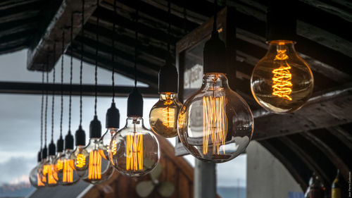 Low angle view of illuminated light bulbs hanging from roof