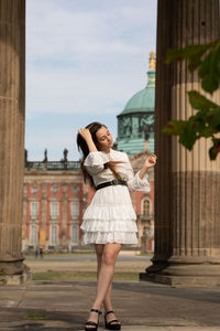 Full length of woman standing against building in city