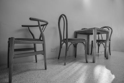 Empty chairs and table against wall