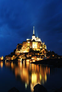 Illuminated mont saint-michel by sea against sky at night