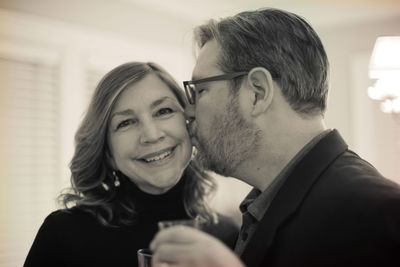 Man kissing smiling woman at home