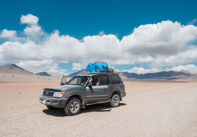 Vintage car on desert land against sky